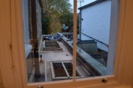 The image shows a neatly organized kitchen window with a small garden view and some roofing materials outside.
AI-generated content may be incorrect.